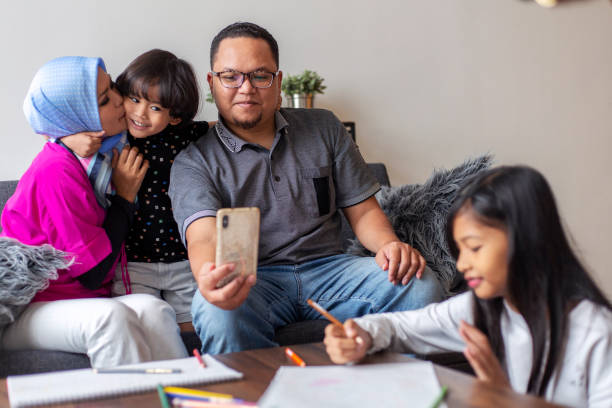 czułe azjatyckie selfie rodzinne ze smartfonem - kredka całują zdjęcia i obrazy z banku zdjęć
