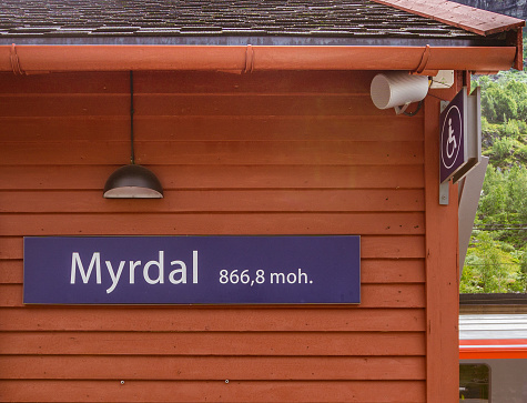 On a red wooden building there is an inscription with the name of the station and the height above sea level. MYRDAL STATION,Norway.