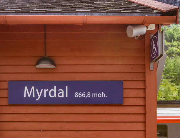 On a red wooden building there is an inscription with the name of the station and the height above sea level. MYRDAL STATION,Norway.