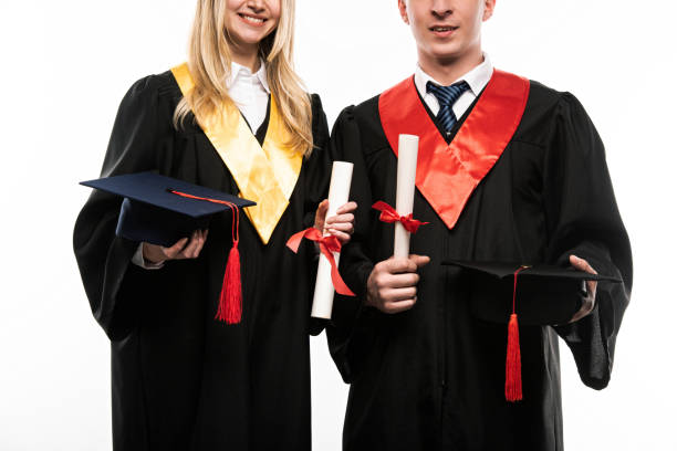 istock Front view of students holding graduation caps and diplomas isolated on white 1207539190