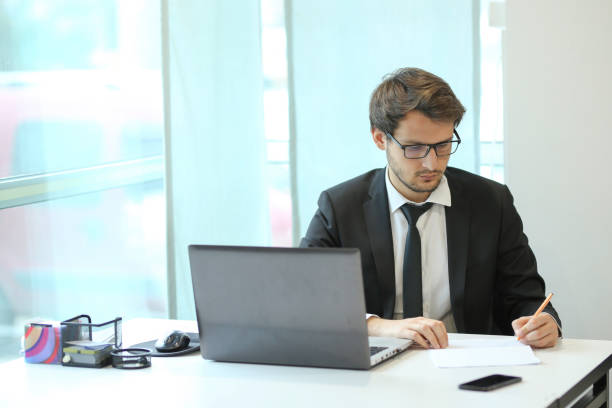 istock Business man working in his office, writing on paper 1207539489