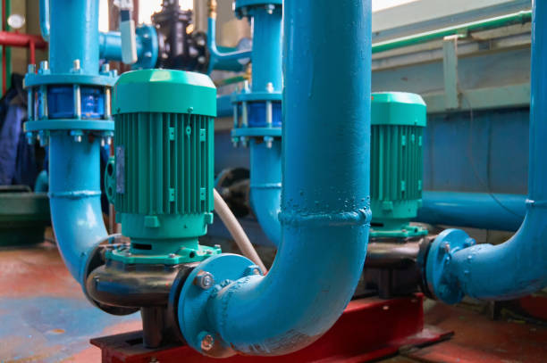 istock Green vertical motors with pumps on a blue colored water pipeline. 1207539494