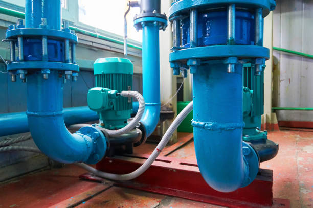 istock Green vertical motors with pumps on a blue colored water pipeline. 1207539536