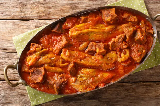 Photo of Khoresh Bademjan Slowly stewed lamb meat with eggplant, spices close-up in a pan. Horizontal top view