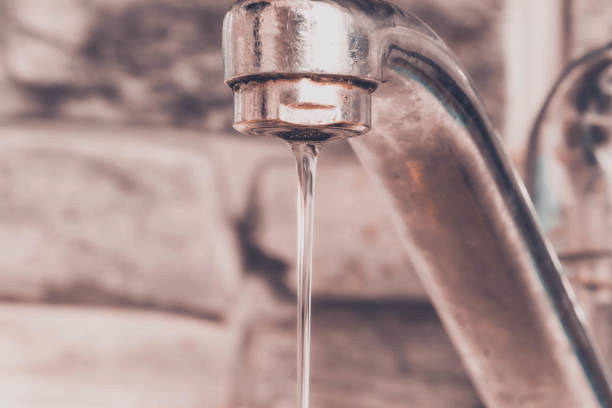 istock Water flows from open crane against the background of brick wall 1207540565