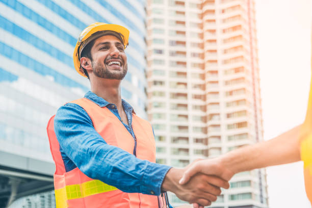 istock Engineer in Yellow helmet and best greeting with warm handshake manager visiting site. Modern construction and engineering concept. Safety of work in production and construction work place. 1207540891