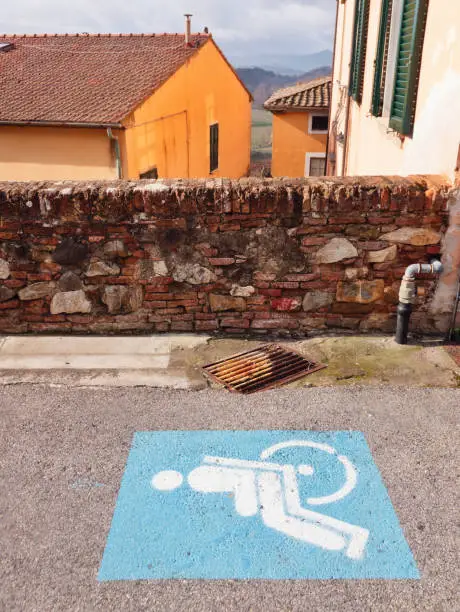 blue and white disabled-parking sign painted on the asphalt in Italy