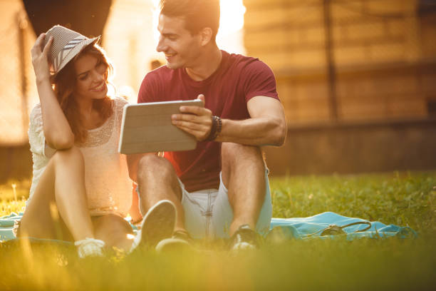 istock Young couple on the grass browsing web pages on a digital tablet 1207541166