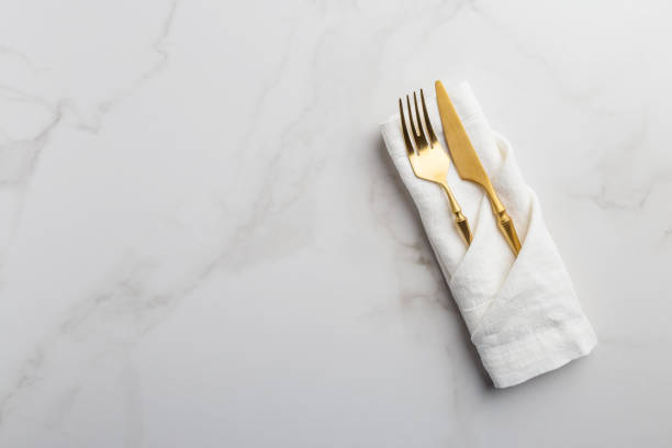 istock Golden tableware at white napkin on white marble background 1207541310
