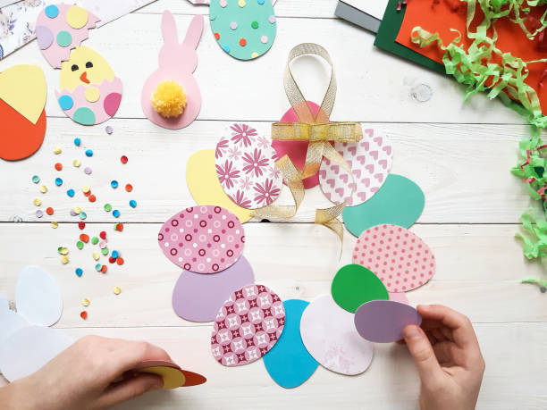 istock The child makes crafts with his own hands for the Easter. Colorful handmade from multi-colored paper. Scissors, cardboard, eggs, chicken, rabbit. Art creativity on a wooden table. Top view, copy space 1207541461