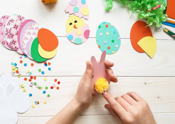 istock The child makes crafts with his own hands for the Easter. Colorful handmade from multi-colored paper. Scissors, cardboard, eggs, chicken, rabbit. Art creativity on a wooden table. Top view, copy space 1207542034