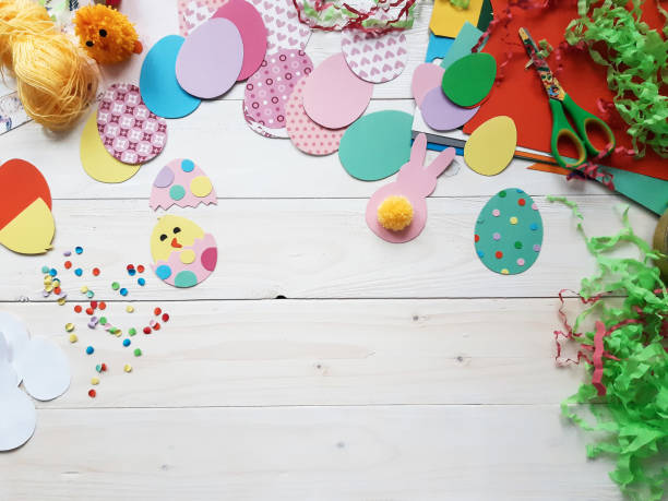 istock The child makes crafts with his own hands for the Easter. Colorful handmade from multi-colored paper. Scissors, cardboard, eggs, chicken, rabbit. Art creativity on a wooden table. Top view, copy space 1207542051