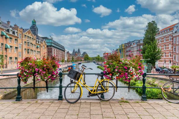 vélo sur un pont au-dessus d’un canal à amsterdam pays-bas avec le ciel bleu - amsterdam photos et images de collection