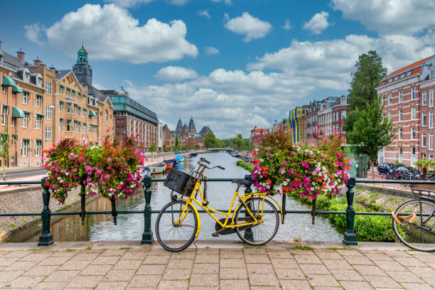fiets op een brug over een kanaal in amsterdam nederland met blauwe hemel - amsterdam stockfoto's en -beelden