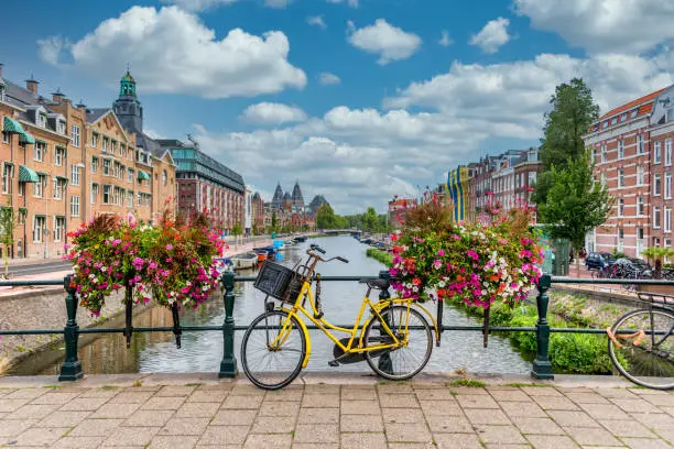 Photo of Bicycle on a Bridge over a Canal in Amsterdam Netherlands with Blue Sky