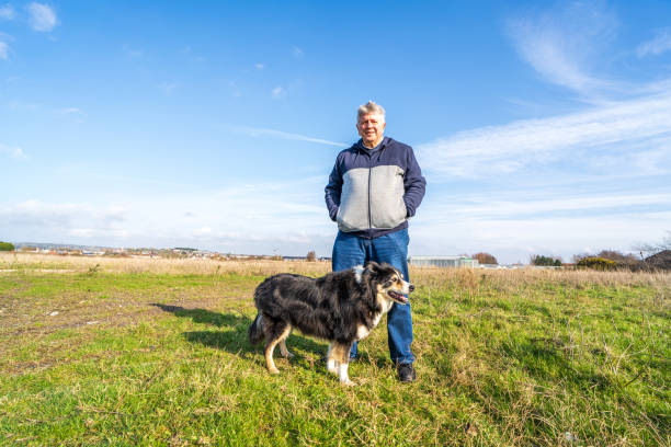 istock Man walking on grassland with border collie 1207547039
