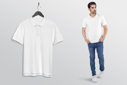 Hanging plan white t shirt on wall. Beside walking male model in blue denim jeans pant. Isolated background.