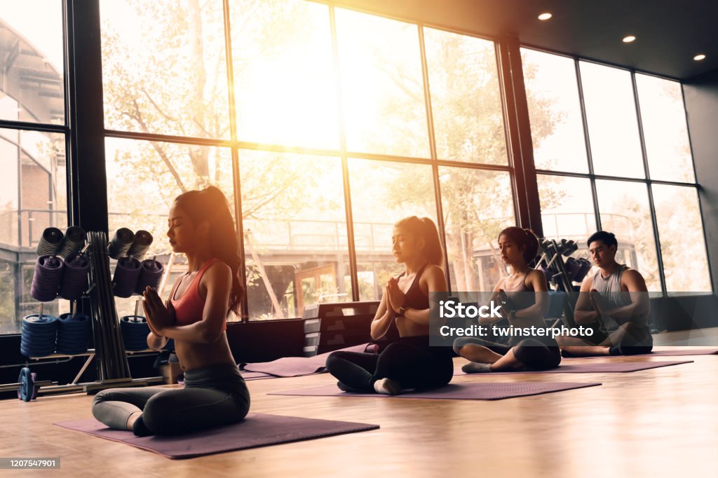 Foto de Grupo De Mulheres Asiáticas E Homens Fazendo Pilates Deitados Em  Tapetes De Yoga Na Aula De Aeróbica Jovens Esportivos De Joelhos Dobrados  No Chão E Colocar As Mãos Para Cima