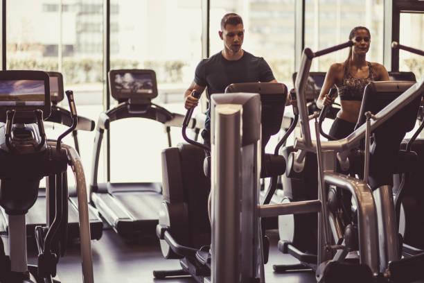 istock Athletic man and woman using elliptical at the gym 1207548129