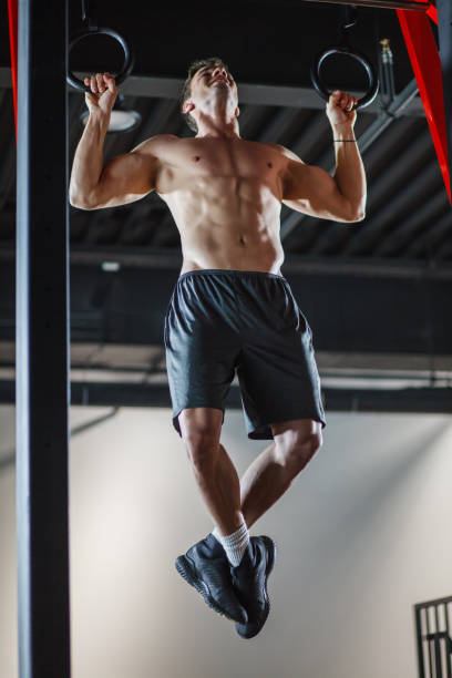 istock Muscular man doing pull ups on gymnastic rings at the gym 1207548944