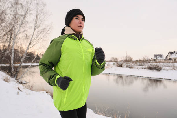 istock Young woman jogging along winter coast 1207549361