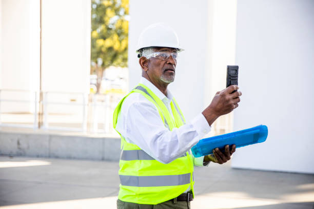 senior black man gerente de construcción tomando fotos con smartphone - trabajador de construcción fotos fotografías e imágenes de stock