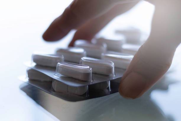 istock Pills in capsules on glass counter and white background 1207554408