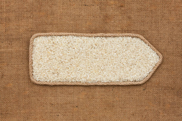 Symbolic pointer made of rope with rice grains lying on a burlap. Top view