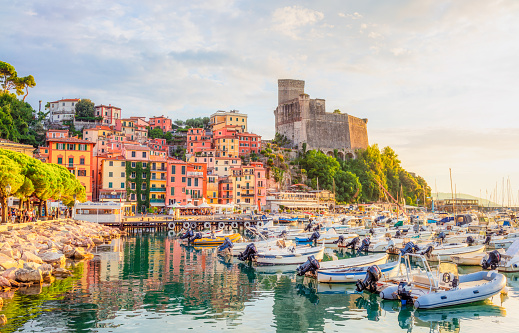 Lerici, Italy - Boats in the town's harbour, with traditional buildings typical of the Liguria region and the Castello di S.Giorgio in the distance.