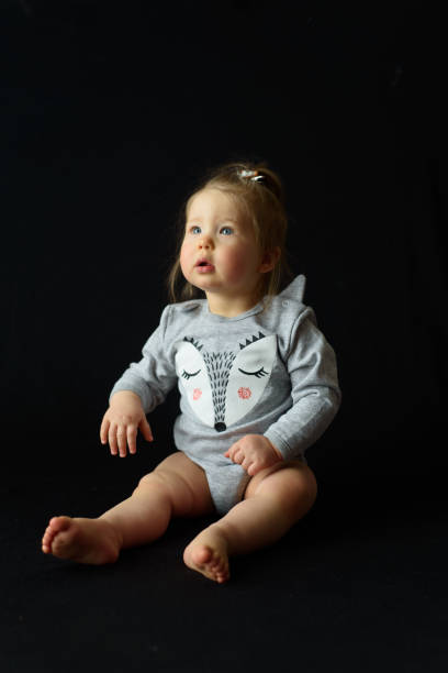 istock little girl sitting on a black background 1207556014