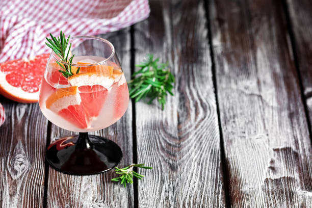 istock Refreshing drink with grapefruit and rosemary in a glass on a wooden rustic table. Selective focus, copy space. Summer cold cocktail. 1207557820