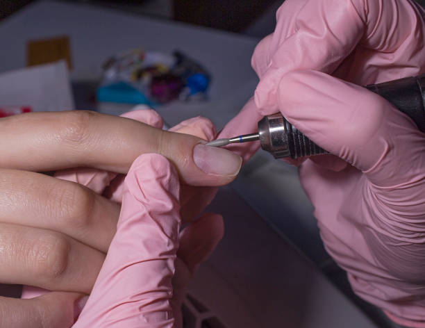 istock The manicurist processes the client's cuticle with a hardware machine. Hardware manicure.Cuticle removal using a machine with a cutter. Professional manicure in the salon close-up. 1207560053