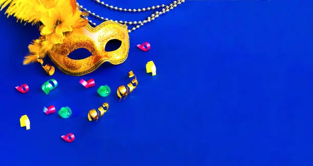 Photo of Carnival mask on blue background with silver beads. Mardi Gras concept. Copy space