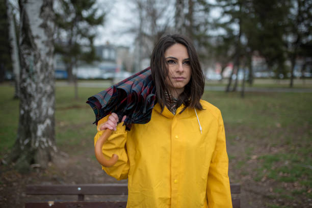 istock Young woman in yellow raincoat spending rainy day in park 1207561544