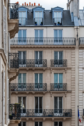 Parisian house with Windows, balconies and roof dormers against a beige wall. From the Windows of the world series.