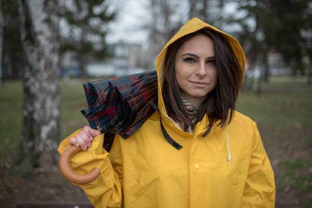 istock Young woman in yellow raincoat spending rainy day in park 1207561587