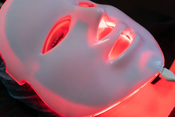 mask for phototherapy on a woman face red glowing cosmetology mask for phototherapy at the spa led stock pictures, royalty-free photos & images
