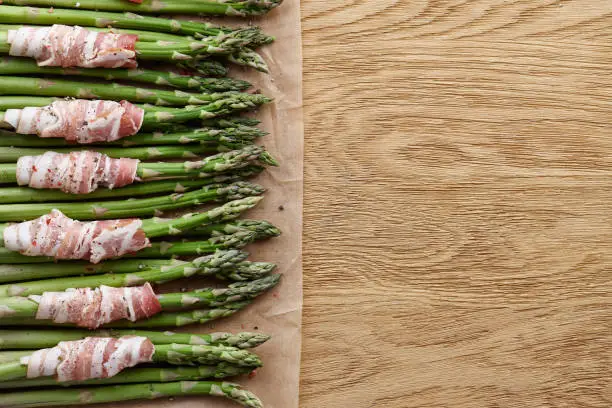 Raw green asparagus wrapped with bacon ready for baking, top view