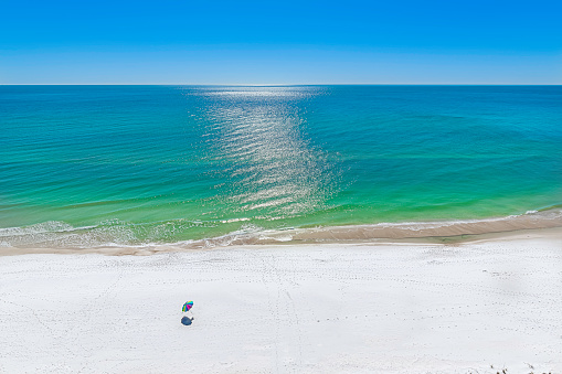 The emerald waters of the gulf of mexico at panama city beach, deserted except for colorful beach umbrella.