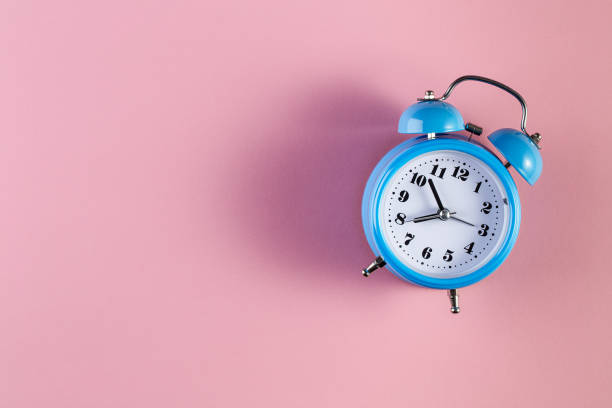 istock Blue vintage alarm clock on light pink color background 1207566082