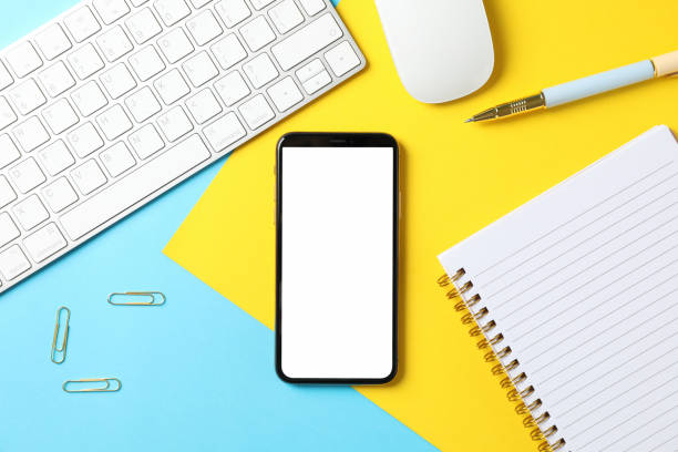 istock Workplace with phone with empty screen on color background, top view 1207566304