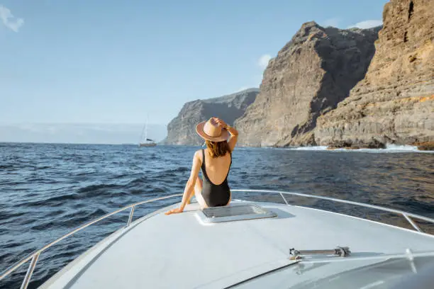 Photo of Woman sailing on the yacht near the rocky coast