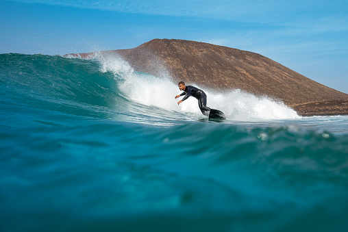 Surfer riding waves on the island of fuerteventura in the Atlantic Ocean, Canary Islands