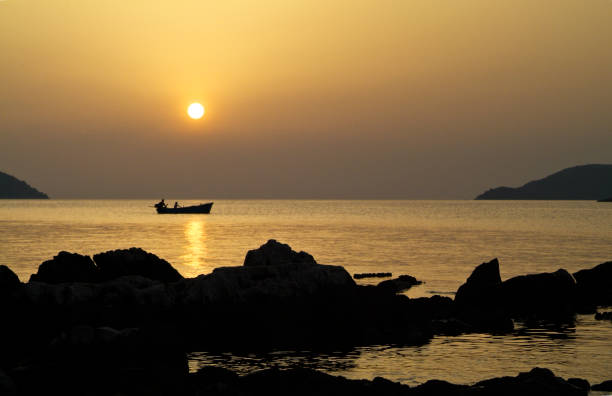 istock Sunset with a small fishing boat 1207570898