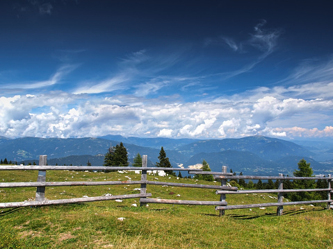 Rural scene with wooden fence in front, Carinthian alps in the background, Austria.