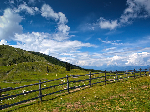 Rural scene with wooden fence in front, Carinthian alps in the background, Austria.