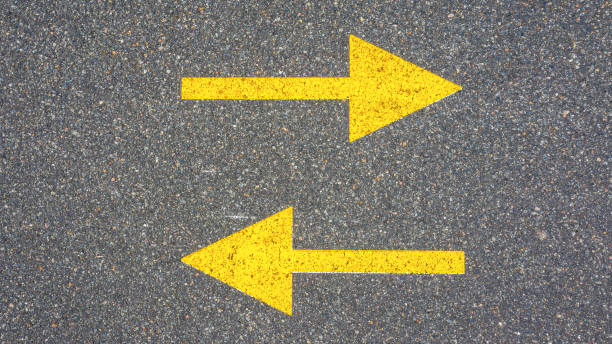 istock Two yellow arrows on the asphalt. Concept, radically different directions. 1207576707