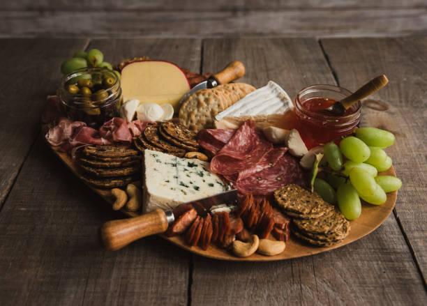 cierre charcutería tabla de carne, queso, galletas sobre mesa de madera. - cheese antipasto cracker grape fotografías e imágenes de stock