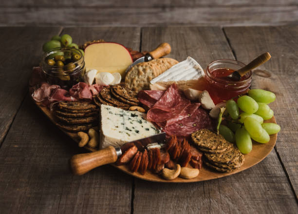 Close up charcuterie board of meat, cheese, crackers on wooden table. Close up charcuterie board of meat, cheese, crackers on wooden table. in Kingston, ON, Canada prosciutto brie stock pictures, royalty-free photos & images