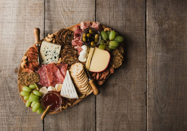 vista dall'alto del tagliere di salumi di carne, formaggio, cracker su tavolo in legno. - cheese antipasto cracker grape foto e immagini stock